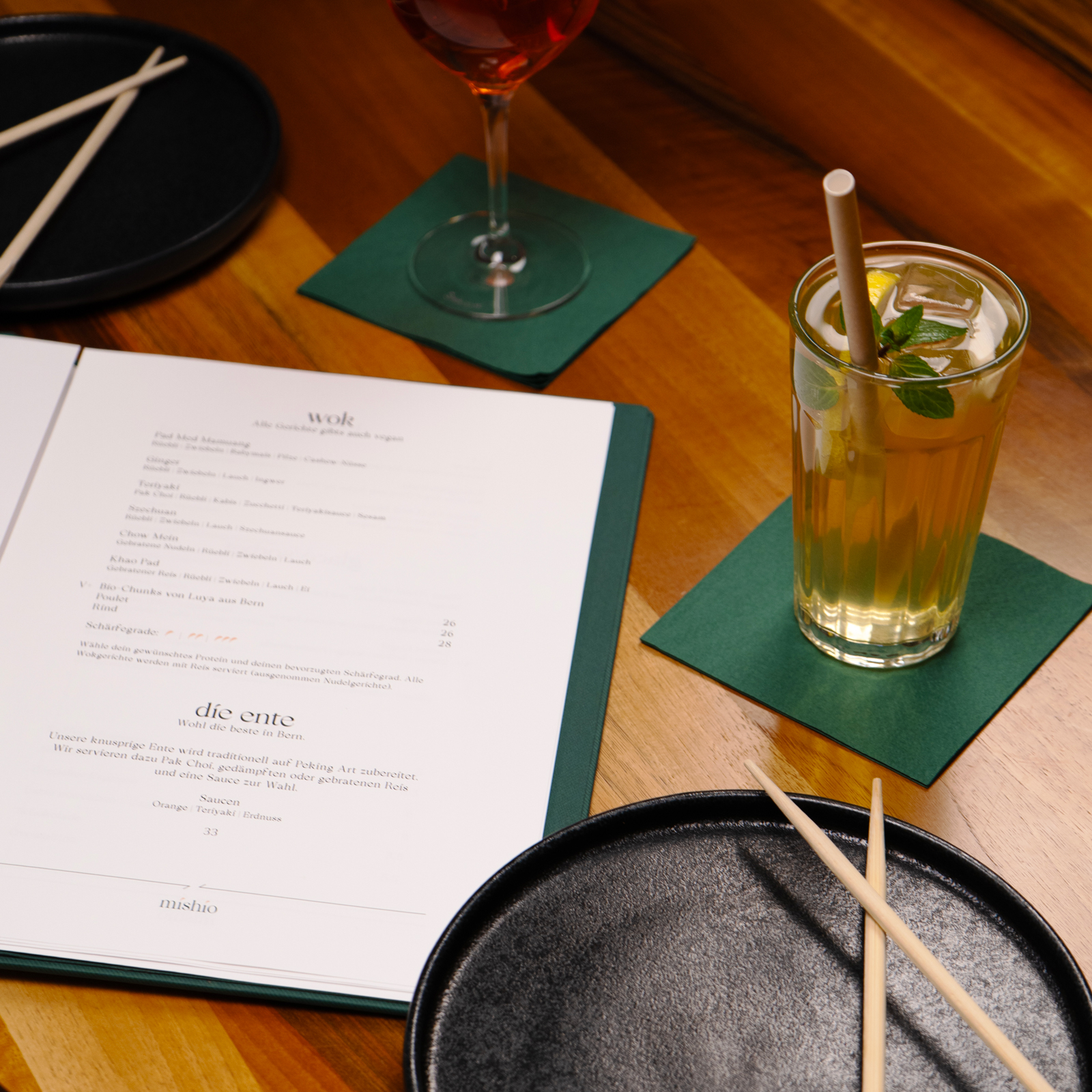 Ansicht eines Tisches im Mishio Bern mit geöffneter Speisekarte, Tellern und Getränken
